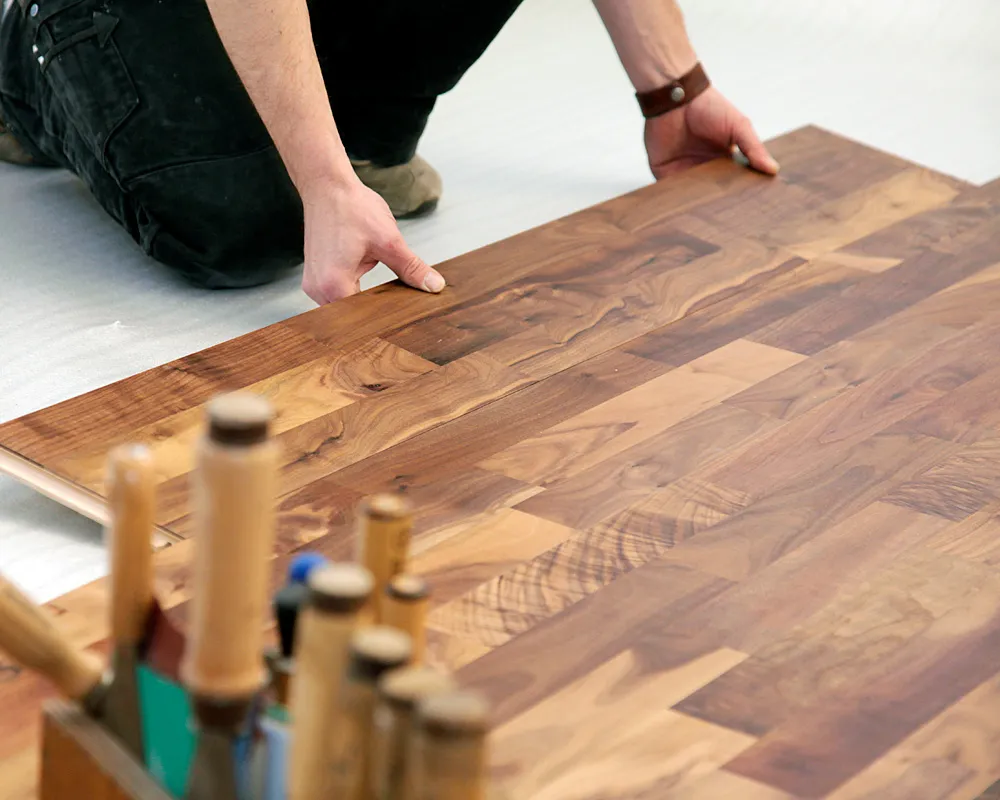 Handwerker verlegt Laminat in Nussbaumoptik mit präzisem Klicksystem