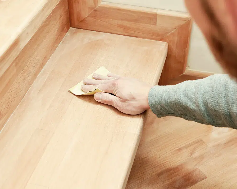 Treppenrenovierung: Feinschliff einer Trittstufe von Hand mit Schleifpapier