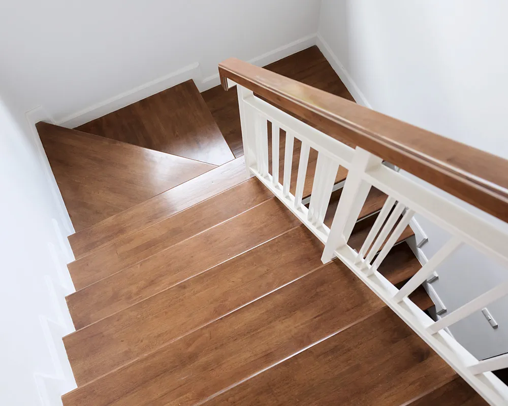 Sanierte Treppe mit neuen Holzstufen und weißem Geländer mit Holzhandlauf