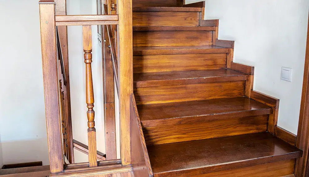 Geschlossene Holztreppe mit zerkratzten Trittflächen und Setzstufen