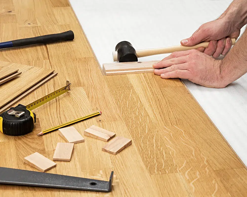 Handwerker verlegt Laminatdielen mit Schlagklotz und Hammer in Filderstadt